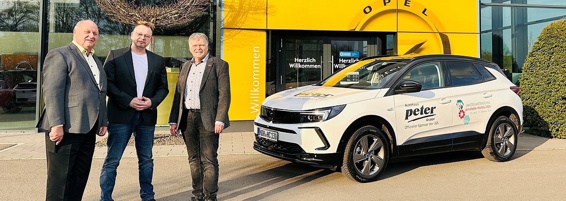 Vor dem Opel-Autohaus mit gelbem Eingang stehen Helmut Peter, Gesch&auml;ftsf&uuml;hrer der Peter-Gruppe, Stefan Nolte von der Landesgartenschau und Achit T&ouml;lle, Centerleiter Opel Nordhausen. Rechts im Bild ein wei&szlig;er Opel SUV mit Beschriftung �Autohaus Peter � Offizieller Sponsor der LGS�, &uuml;bergeben an das LAGA-Planungsteam.