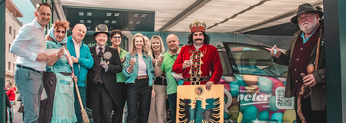 Mehrere Personen auf der Skoda-Roadshow-B&uuml;hne (4 davon kost&uuml;miert), alle schauen in die Kamera; daneben ein bunt beklebtes Fahrzeug


