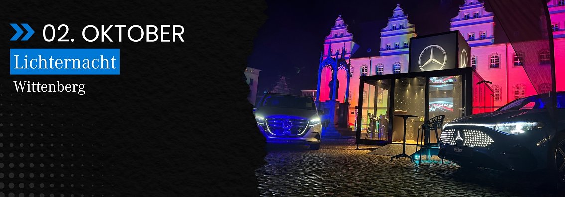 Der Marktplatz von Wittenberg bei D&auml;mmerung: Das historische Rathaus ist bunt angestrahlt, davor mehrere beleuchtete Mercedes-Benz Fahrzeuge und ein Stand des Autohauses Peter mit gro&szlig;em Mercedes-Stern.