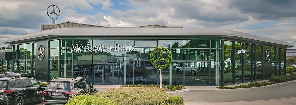 Au&szlig;enansicht des Mercedes-Benz Autohauses (Stammsitz der Peter Gruppe) in Nordhausen. Das moderne Glasgeb&auml;ude tr&auml;gt den Mercedes-Schriftzug und das Logo, davor stehen mehrere schwarze Autos, dar&uuml;ber ein gro&szlig;er Mercedes-Stern auf dem Dach.