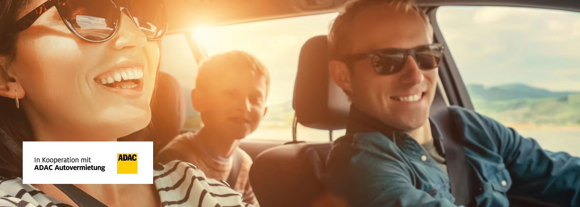Fr&ouml;hliche Familie mit Sonnenbrillen f&auml;hrt Auto, sonnige Landschaft im Hintergrund; links unten ADAC-Logo mit Text In Kooperation mit ADAC Autovermietung.