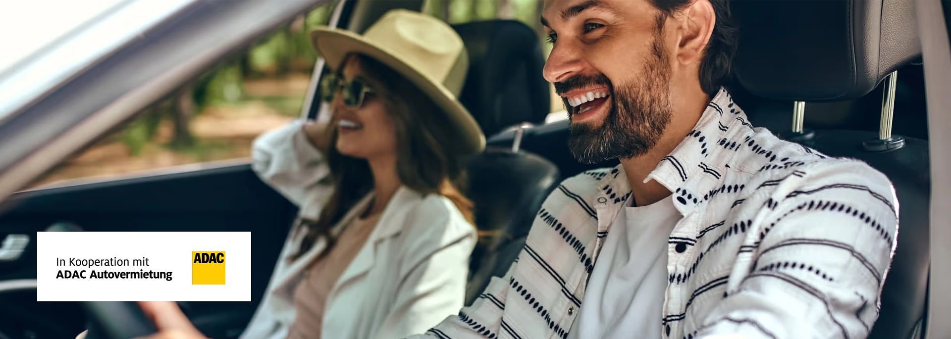 Fr&ouml;hliches Paar mit Sonnenbrillen im Auto; die Frau tr&auml;gt einen Hut, beide lachen. Links unten ADAC-Logo mit Text In Kooperation mit ADAC Autovermietung.