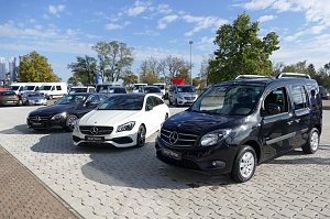 Mehrere schwarze und weiße Mercedes �Junge Sterne� Gebrauchtwagen, darunter Limousinen und ein Hochdachkombi, auf einem gepflasterten Autohaus-Areal bei sonnigem Wetter.