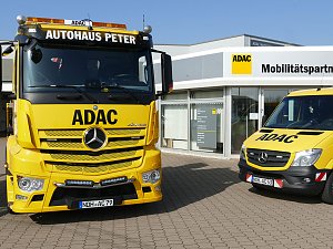 Zwei gelbe ADAC-Fahrzeuge vor dem Gebäude des ADAC Mobilitätspartners Peter in Nordhausen. Links ein großer Abschlepp-Lkw mit der Aufschrift "Autohaus Peter", rechts ein kleinerer Pannenhilfswagen. Im Hintergrund das moderne Gebäude mit Glasfront und ADAC-Logo.