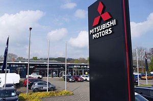 Außenansicht des Peter-Mehrmarkenhauses in Göttingen mit großem Mitsubishi-Motors-Schild im Vordergrund und mehreren Fahrzeugen auf dem Parkplatz.