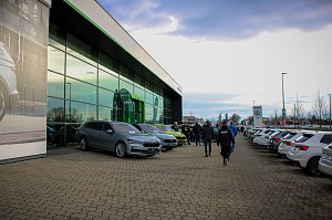 Das �koda Autohaus mit moderner Glasfassade. Vor dem Gebäude stehen mehrere neue �koda-Fahrzeuge, Besucher gehen zwischen den Autos hindurch.
