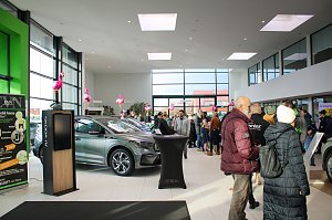 Großer Ausstellungsraum mit neuen �koda-Fahrzeugen. Viele Menschen gehen durch die Halle. Rosa Flamingos sind als Dekoration aufgestellt.