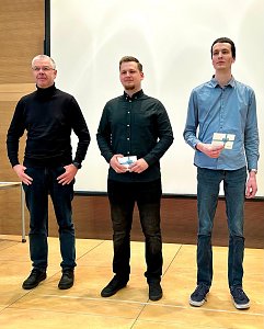 Robert Rausch und Florian Kahl stehen neben ihrem Berufsschullehrer. Beide halten einen Geschenkgutschein, während sie für die Auszeichnung posieren.