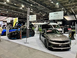 Zwei moderne Opel-Modelle, ein schwarzer und ein grauer Wagen, stehen auf der Ausstellungsfläche der Autohaus Peter Gruppe. Im Hintergrund Wohnmobile und große Banner.