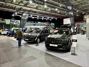 Zwei schwarze Jeep Compass Modelle mit geöffneten Motorhauben und Jeep-Bannern stehen nebeneinander, Besucher betrachten die Fahrzeuge.
