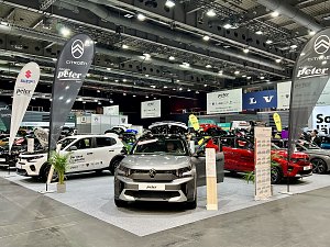 Ein grauer Citroën SUV und ein weißer Citroën C3 sind ausgestellt, mit Citroën-Fahnen und weiteren Markenständen im Hintergrund.