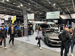 Blick auf mehrere Opel-Fahrzeuge, darunter ein grauer Opel mit offener Motorhaube und ein Wohnmobil. Besucher laufen über die Messefläche.