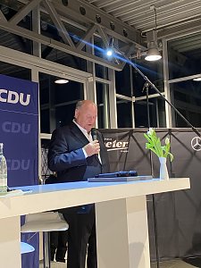 Helmut Peter spricht am Pult mit Mikrofon. Hinter ihm CDU-Banner und Autohaus-Logo Peter.