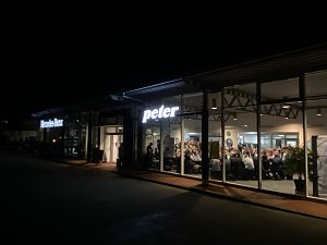 Das Autohaus Peter in Duderstadt bei Nacht. Durch die Fenster ist der volle Saal mit zahlreichen G&auml;sten sichtbar.