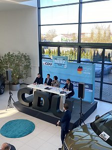Blick leicht von oben auf Podiumsdiskussion mit vier Teilnehmenden, darunter Colette Boos-John. Vor der Bühne große schwarze CDU-Buchstaben, im Hintergrund ein Skoda-Auto.