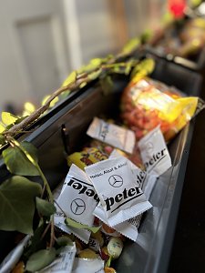 Detailaufnahme von Bonbons mit der Aufschrift �Helau, Alaaf & Ahoi!� und dem Autohaus-Peter-Logo, dekoriert mit Efeuranken, im Hintergrund weitere Süßigkeiten.