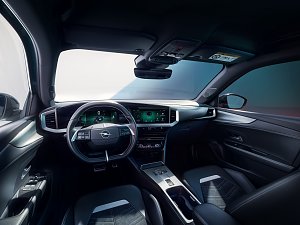 Innenraum des Opel Mokka Electric mit modernem digitalen Cockpit, großem zentralen Infotainment-Bildschirm und Lederlenkrad, Blick vom Fahrersitz nach vorn.