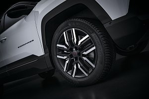 Nahaufnahme des Vorderrads eines weißen Jeep Compass mit schwarzer und silberner Leichtmetallfelge, Michelin CrossClimate-Reifen und sichtbarem Compass-Schriftzug an der Seite.