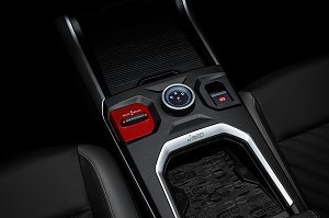 Nahaufnahme der Mittelkonsole mit Wählrad für Fahrstufen (R, N, D, P), rotem Select Terrain-Schalter, elektronischer Parkbremse und Ablagefläche mit Jeep-Logo.