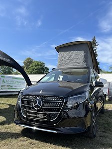 Mercedes-Benz Van mit Aufstelldach: Schwarzer Mercedes-Benz Van mit geöffnetem Aufstelldach auf der Messefläche.
