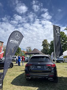 Rückansicht SUV mit Fahnen: Schwarzer Mercedes-Benz SUV von hinten, flankiert von Fahnen der Autohaus Peter Gruppe und Mercedes-Benz.