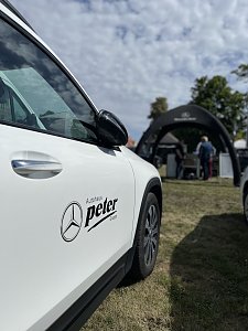 Weißer Mercedes-Benz mit Logo: Seitliche Nahaufnahme eines weißen Mercedes-Benz mit Autohaus-Peter-Logo, im Hintergrund der Messestand.