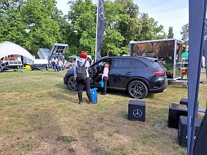 SUV mit Besuchern: Schwarzer Mercedes-Benz SUV, in den eine Frau mit Kind hineinschaut, umgeben von weiteren Ausstellungsflächen.