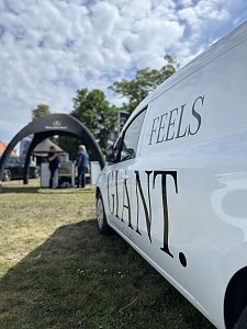 Weißer Transporter mit Schriftzug: Seitliche Nahaufnahme eines weißen Fahrzeugs mit dem Schriftzug Feels Giant auf der Messefläche.