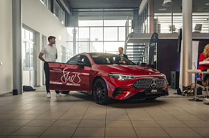  Roter Mercedes-Benz CLA 250+ mit Aufschrift She�s Mercedes auf der Fahrert&uuml;r, zwei M&auml;nner stehen daneben in einer Ausstellungshalle. Mercedes-Benz CLA 250+ mit EQ-Technologie | Energieverbrauch kombiniert: 14,1-12,2 kWh/100 km | CO2Emissionen kombiniert: 0 g/km | CO2-Emissionsklasse: A