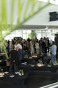Blick in den Ausstellungsraum des Autohauses Peter beim südafrikanischen Abend in Heiligenstadt. Zahlreiche Gäste stehen in Gruppen zusammen, unterhalten sich und genießen die entspannte Atmosphäre zwischen dekorierten Stehtischen und Fahrzeugen.