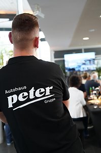 Ein Mitarbeiter der Autohaus Peter Gruppe mit Rückenansicht während des südafrikanischen Abends in Heiligenstadt, im Hintergrund sitzen Gäste an festlich gedeckten Tischen