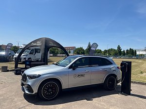 Ein silberner Mercedes-Benz SUV mit Autohaus-Peter-Logo steht bei einer Präsentation im Freien am Ladegerät. Im Hintergrund sind ein schwarzes Zelt mit der Aufschrift �Jetzt Probe fahren�, Fahnen und weitere Fahrzeuge zu sehen. Die Szene gehört zum Leichtathletik-Meeting Anhalt 2025.