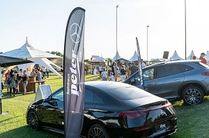 Besucher schlendern über die Wiese des Reitturniers in Immenrode mit weißen Pagodenzelten und Getränkeständen. Im Vordergrund stehen zwei Mercedes-Benz Fahrzeuge neben Fahnen des Autohauses Peter.