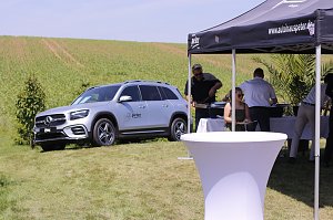 Ein silberner Mercedes-Benz SUV steht auf einer grünen Wiese neben einem schwarzen Pavillon des Autohauses Peter. Unter dem Zelt servieren Mitarbeiter Speisen an die Besucher des Reitturniers in Immenrode.