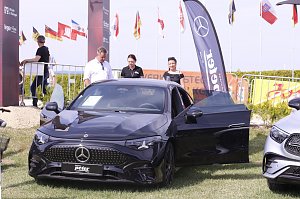 Ein schwarzes Mercedes-Benz Fahrzeug steht mit geöffneter Fahrertür auf der Ausstellungsfläche beim Reitturnier in Immenrode. Dahinter stehen drei Erwachsene, im Hintergrund sind Fahnen, Absperrgitter und ein Werbebanner des Autohauses Peter zu sehen.