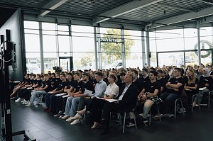 Reihe neuer Auszubildender der Autohaus-Peter-Gruppe sitzt in der Firmenzentrale in Nordhausen. Alle tragen schwarze T-Shirts mit Firmenlogo und hören der Auftaktveranstaltung aufmerksam zu.