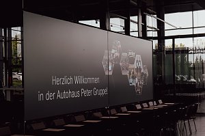 Leinwand mit der Begrüßung �Herzlich willkommen in der Autohaus Peter Gruppe!� in der Firmenzentrale in Nordhausen. Auf der Leinwand sind auch Fotos von Mitarbeitern und Azubis zu sehen.