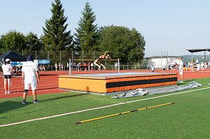 Athletin überspringt im Rückwärtssprung die Hochsprunglatte. Kampfrichter und Zuschauer beobachten den Versuch.