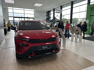 Ein roter �koda Elroq steht im Ausstellungsraum des Autohauses Autowelt Peter. Im Hintergrund stehen und unterhalten sich mehrere Besucher, daneben befinden sich Infostände und ein Bereich mit Sitzgelegenheiten.