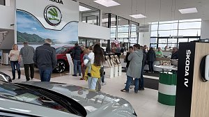 Besucherinnen und Besucher im Autohaus Autowelt Peter während der Jubiläumsfeier zu 130 Jahren �koda. Im Ausstellungsraum stehen Fahrzeuge, Kranzdekorationen und ein Tisch mit Sektgläsern.