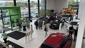 Blick von oben in den Ausstellungsraum des Autohauses Autowelt Peter während der Jubiläumsfeier zu 130 Jahren �koda. Besucherinnen und Besucher schauen sich verschiedene Fahrzeuge an, Mitarbeitende in grünen Shirts beraten. Im Hintergrund steht eine bunte Hüpfburg für Kinder.