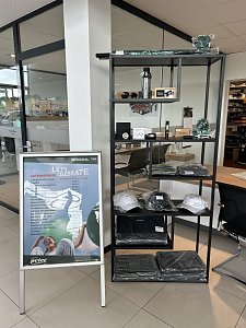 Vitrine mit �koda-Merchandising-Artikeln wie Mützen, Flaschen und Accessoires im Autohaus Autowelt Peter. Daneben ein Aufsteller mit der Aufschrift �Let�s Celebrate � Aktionspreise�.