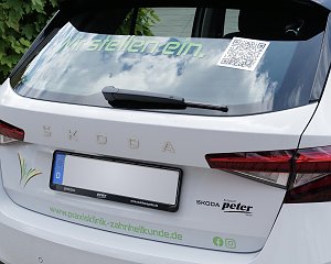 Das Heck eines weißen �koda-Fahrzeugs mit der Aufschrift Wir stellen ein. und einem QR-Code auf der Heckscheibe. Darunter ist das Logo der Klinik zu sehen.