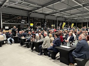 Ein gef&uuml;llter Veranstaltungsraum im Autohaus Peter: viele Anwesende sitzen an schwarzen Tischen und h&ouml;ren einem Redner zu. Im Hintergrund sind Fahrzeuge mit Jeep- und Citro&euml;n-Logos zu sehen.
