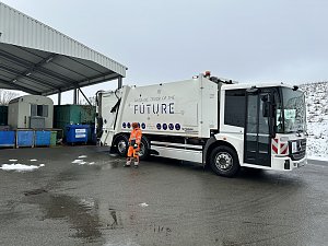 Müllfahrzeug Garbage Truck of the Future steht an einer Sammelstelle neben Containern.