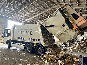 Müllfahrzeug kippt Papier- und Kartonabfälle in einer Recyclinghalle ab.