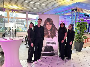 Vier Personen vor L�Oréal-Stand mit Werbebanner und Eventbeleuchtung.