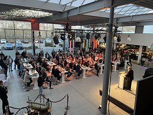 Der Blick von der Galerie auf die Veranstaltung: Helmut Peter am Rednerpult, viele Gäste hören ihm zu.