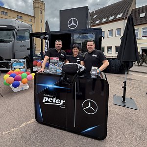 Man sieht drei Mitarbeiter vom Autohaus Peter hinter dem Counter am Promotion-Stand.