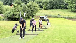 Golferinnen und Golfer trainieren ihre Schläge auf der Driving Range des Golfplatzes.